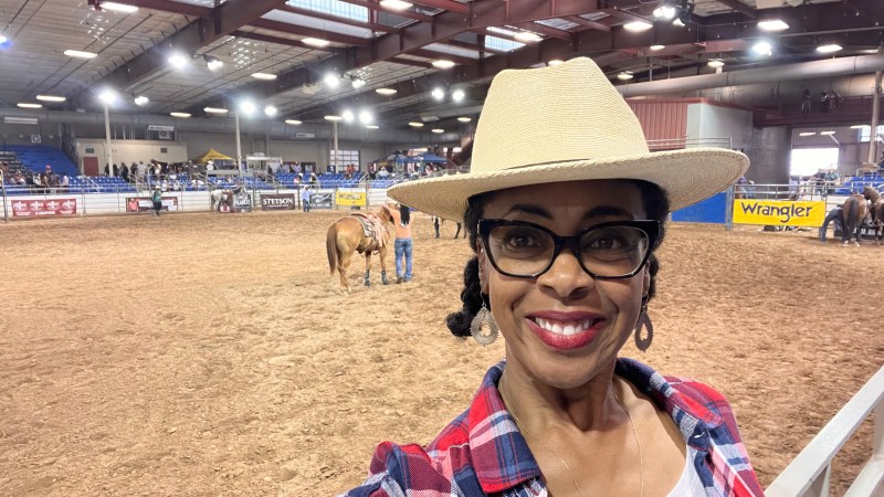 Woman in cowboy hat with rodeo ring behind her
